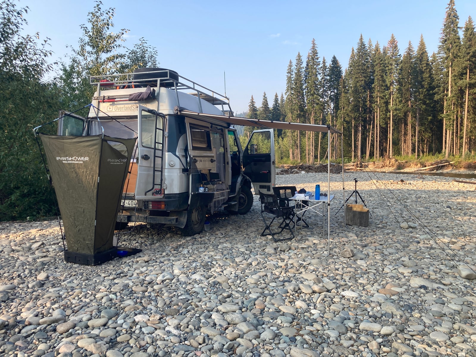A camp on a river bed with the awning out and a shower tent pitched
